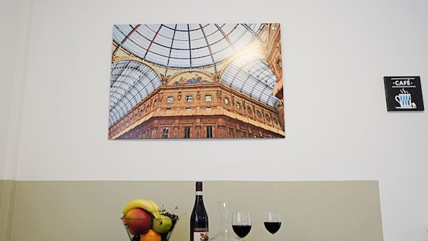Un comedor con una mesa dispuesta para dos, una botella de vino y un bol de fruta.