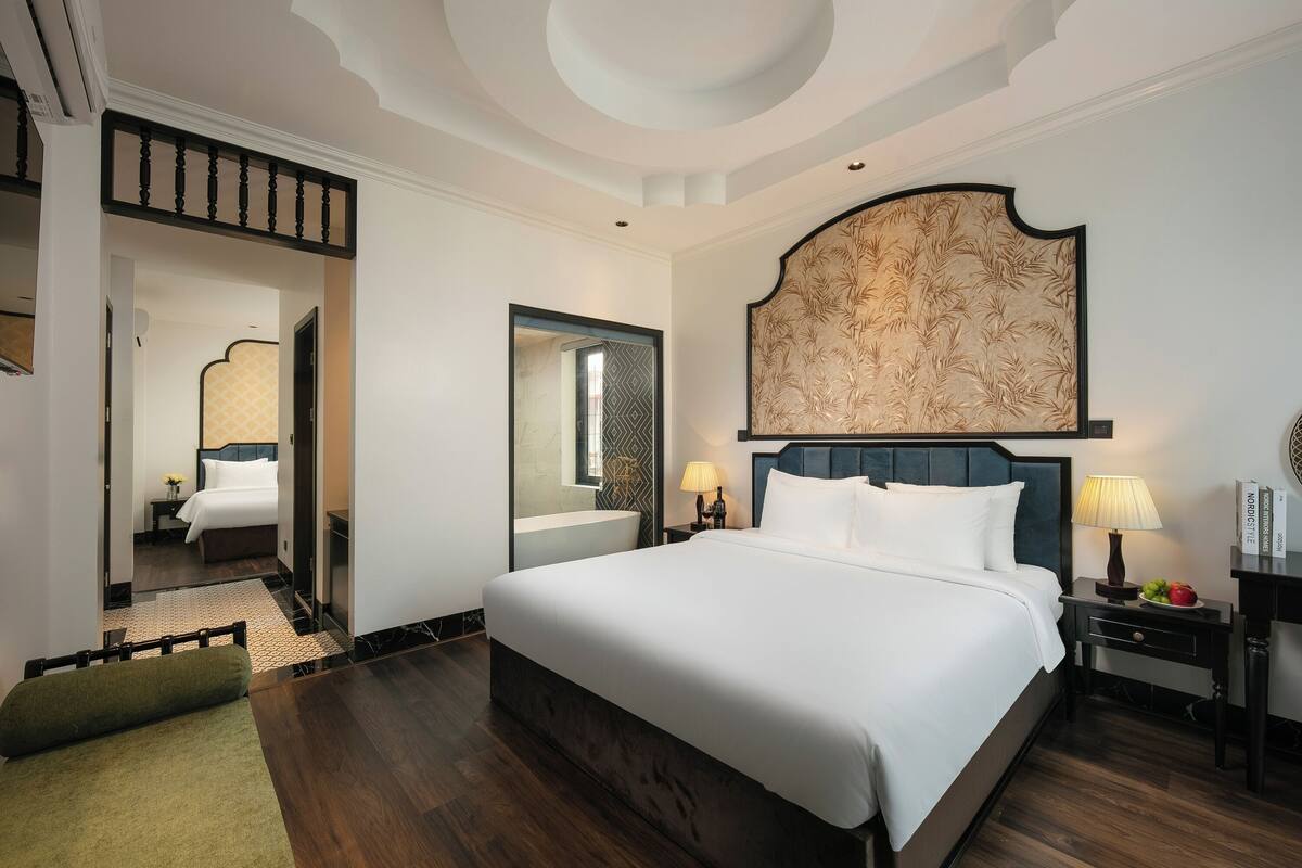 Une chambre d’hôtel avec un grand lit, une tête de lit en bois, une table de chevet avec une lampe et un miroir.