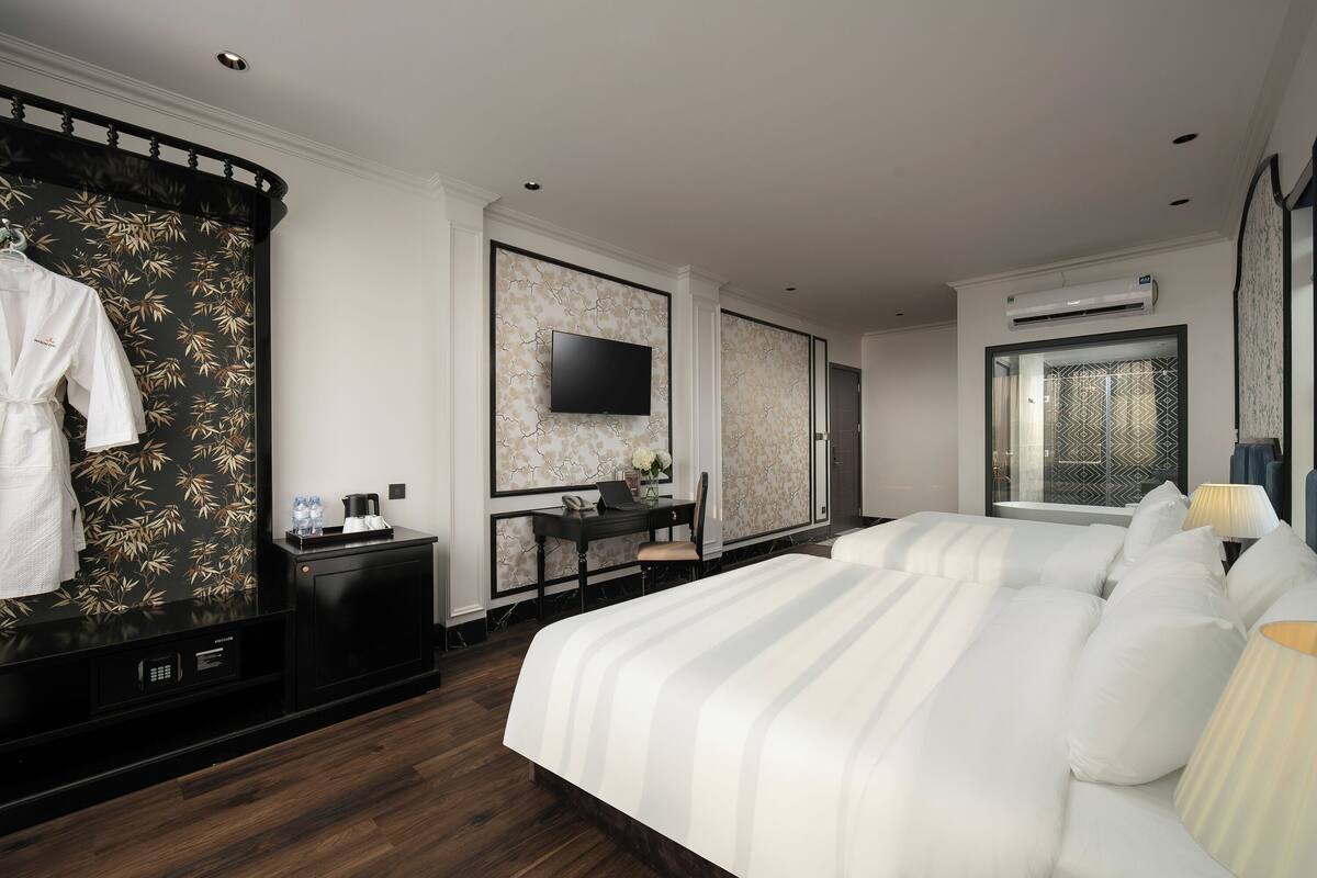 Une chambre d’hôtel avec un grand lit, un bureau avec une chaise, un téléviseur fixé au mur et un appareil de climatisation.