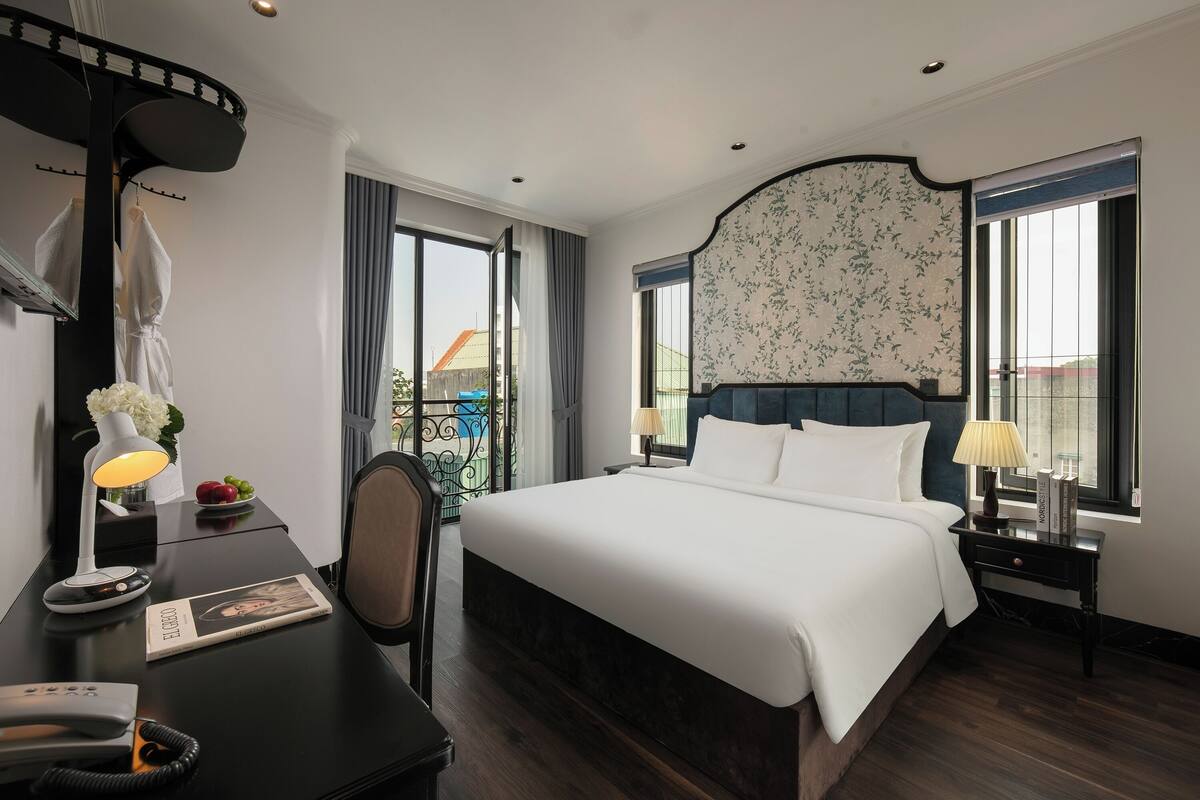 Une chambre d’hôtel avec un grand lit, des tables de chevet avec des lampes, un bureau avec un téléphone et une chaise.