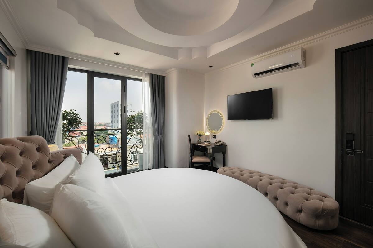 Une chambre dotée d’un grand lit, d’une coiffeuse avec un miroir, d’un téléviseur à écran plat et d’un appareil de climatisation.