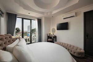 Un dormitorio con una cama grande, una tocador con espejo, un televisor de pantalla plana y un equipo de aire acondicionado.