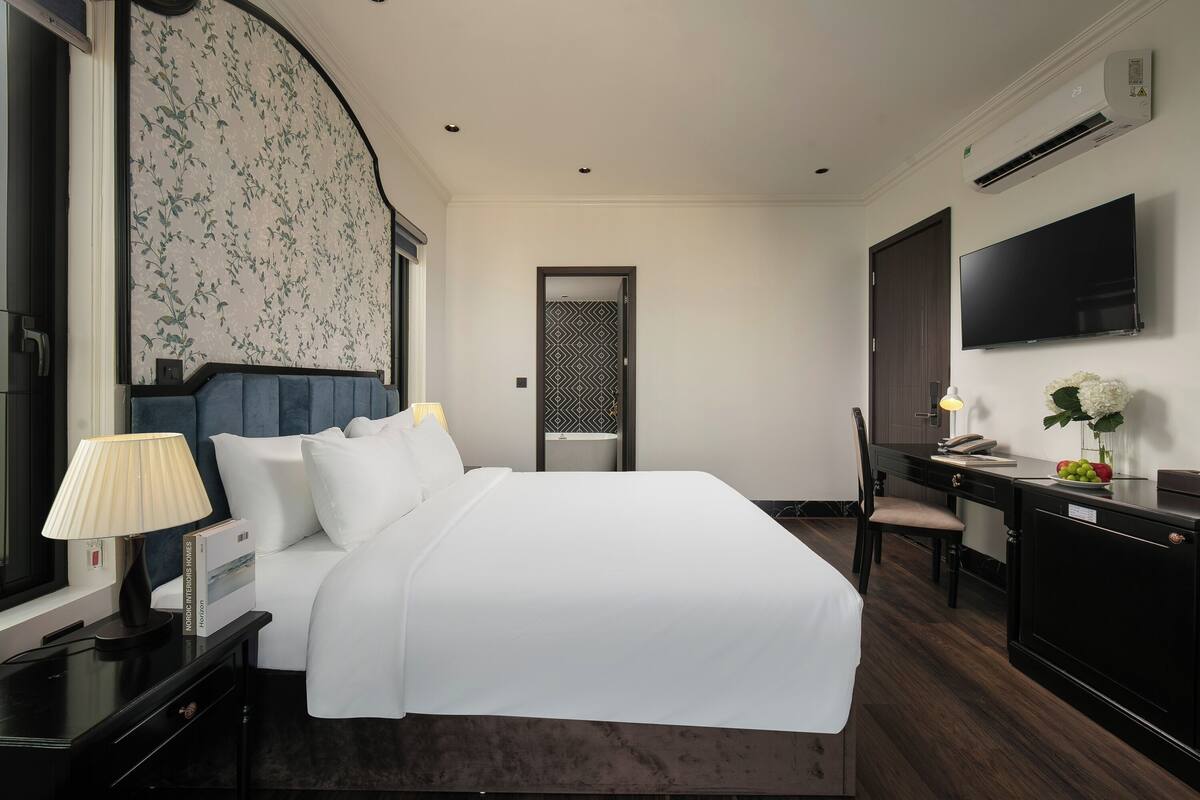 Une chambre d’hôtel avec un grand lit, un bureau avec une chaise, une télévision et un appareil de climatisation.