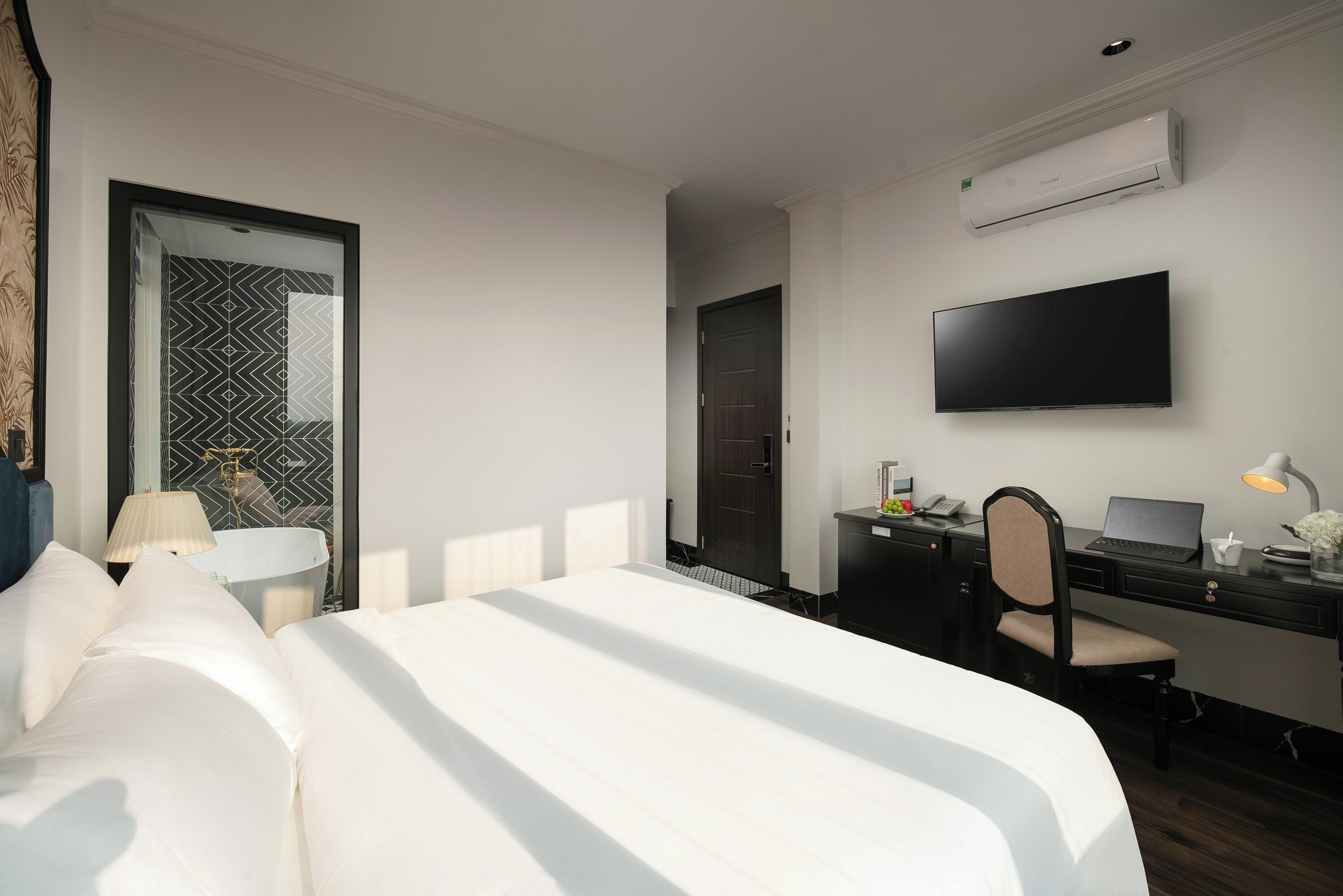 Une chambre d’hôtel équipée d’un lit, d’un bureau, d’une chaise, d’une télévision et d’un appareil de climatisation.