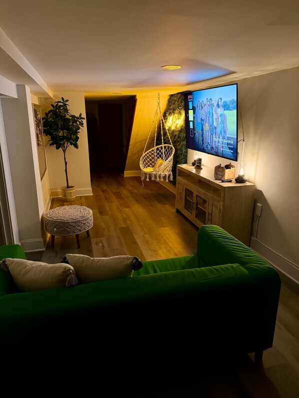 Relax in this stylish living room with a green sofa, ottoman, and hanging chair.