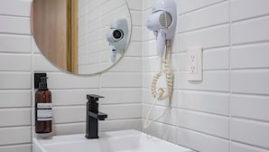A bathroom with a white sink, a hand soap dispenser, a hair dryer, and a mirror. - Comfortable Private Suite in Condesa area (18) (Mexico)