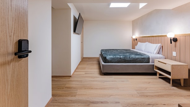 A bedroom with a bed, bedside table, wall-mounted TV, and a wooden headboard. - Comfortable Private Suite in Condesa area (18) (Mexico)