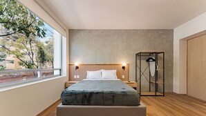 Un dormitorio moderno con una cama grande, suelo de madera, vistas al exterior y un armario empotrado.