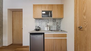 Una cocina compacta con gabinetes de madera, microondas integrado, cafetera y lavavajillas.