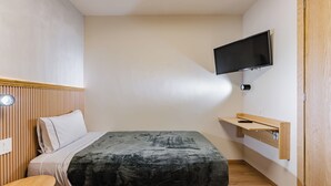 A compact bedroom with a bed, a small table, a mounted TV, and a wooden door. - Comfortable Private Suite in Condesa area (18) (Mexico)