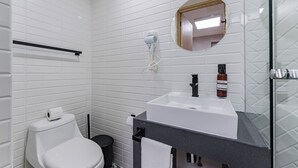 A modern bathroom with white tiles, a white toilet, a black sink, a mirror, and a handheld hair dryer. - Comfortable Private Suite in Condesa area (18) (Mexico)