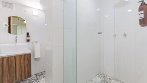 Ein modernes Badezimmer mit Duschkabine aus Glas, Holzwaschtisch und Bodenfliesen mit Muster.