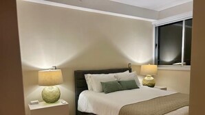 A bedroom with a bed, two bedside tables, lamps, a window, and a nightstand. - Ph Quartier Boutique 16C apt with rooftop pool (Panamá)