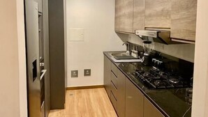 A compact kitchen with a built-in stove, a sink, and a refrigerator. - Ph Quartier Boutique 16C apt with rooftop pool (Panamá)