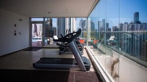 A modern gym with treadmills and a city view. - Ph Quartier Boutique 16C apt with rooftop pool (Panamá)