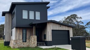 Et moderne hus med to etager, garage, stensokkel og facade i en blanding af træ og metal.