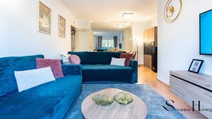 A modern living room with a blue sofa, a coffee table, and a dining area in the background. - Mountain Views, Pool & Rooftop: Cozy 2BR for 6 REF034 (Fuengirola)