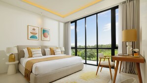 Un dormitorio moderno con una cama grande, una mesita de noche con lámpara, una silla y vistas a la vegetación a través de amplias ventanas.