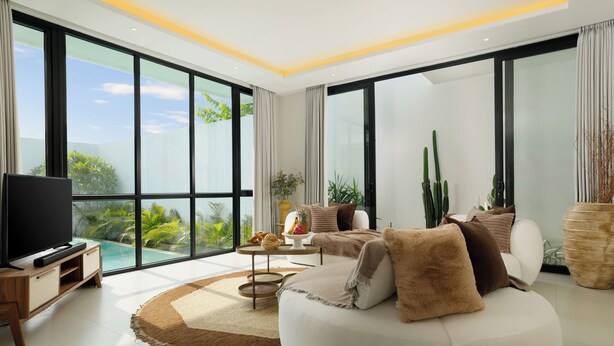 Un salón amplio con un televisor grande, asientos cómodos, una mesita de centro y vistas a una piscina.