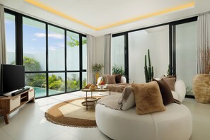 A spacious living room with a large TV, comfortable seating, a coffee table, and a view of a swimming pool. - Villa Kalem Canggu by Nakula (Canggu)