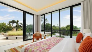 Una habitación de hotel moderna con una cama grande, vistas a zonas verdes y un balcón.