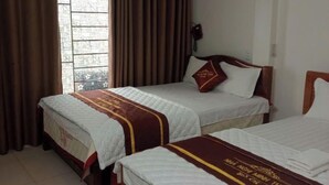 Habitación de hotel con dos camas, una ventana con cortinas, un equipo de aire acondicionado y un teléfono en la pared.