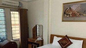 Habitación de hotel con cama, escritorio, silla, aire acondicionado y ventana.