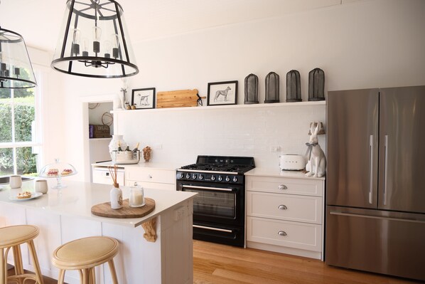 Une cuisine moderne dotée d’un îlot central, d’appareils électroménagers en acier inoxydable et d’un dosseret de carrelage blanc.