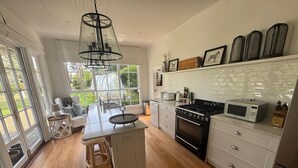 A modern kitchen with a central island, white cabinetry, a black stove, a microwave, and a sink.