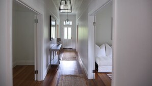 Un couloir doté d’un plancher en bois, de murs blancs et d’un canapé blanc au fond.