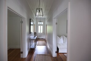 A hallway with a wooden floor, white walls, and a white sofa at the end. - Luxury farm stay just 12 minutes from Braidwood (Durran Durra)