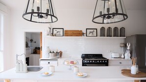 A modern kitchen with white cabinetry, a central island with seating, a gas stove, and pendant lighting.