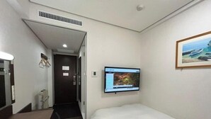 A hotel room with a bed, a desk, a television mounted on the wall, and a door leading to another room. - Hotel Alpha-One Kashiwazaki (Kashiwazaki)