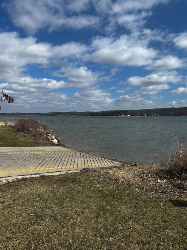 A waterfront view with a dock, grassy area, and a flag.