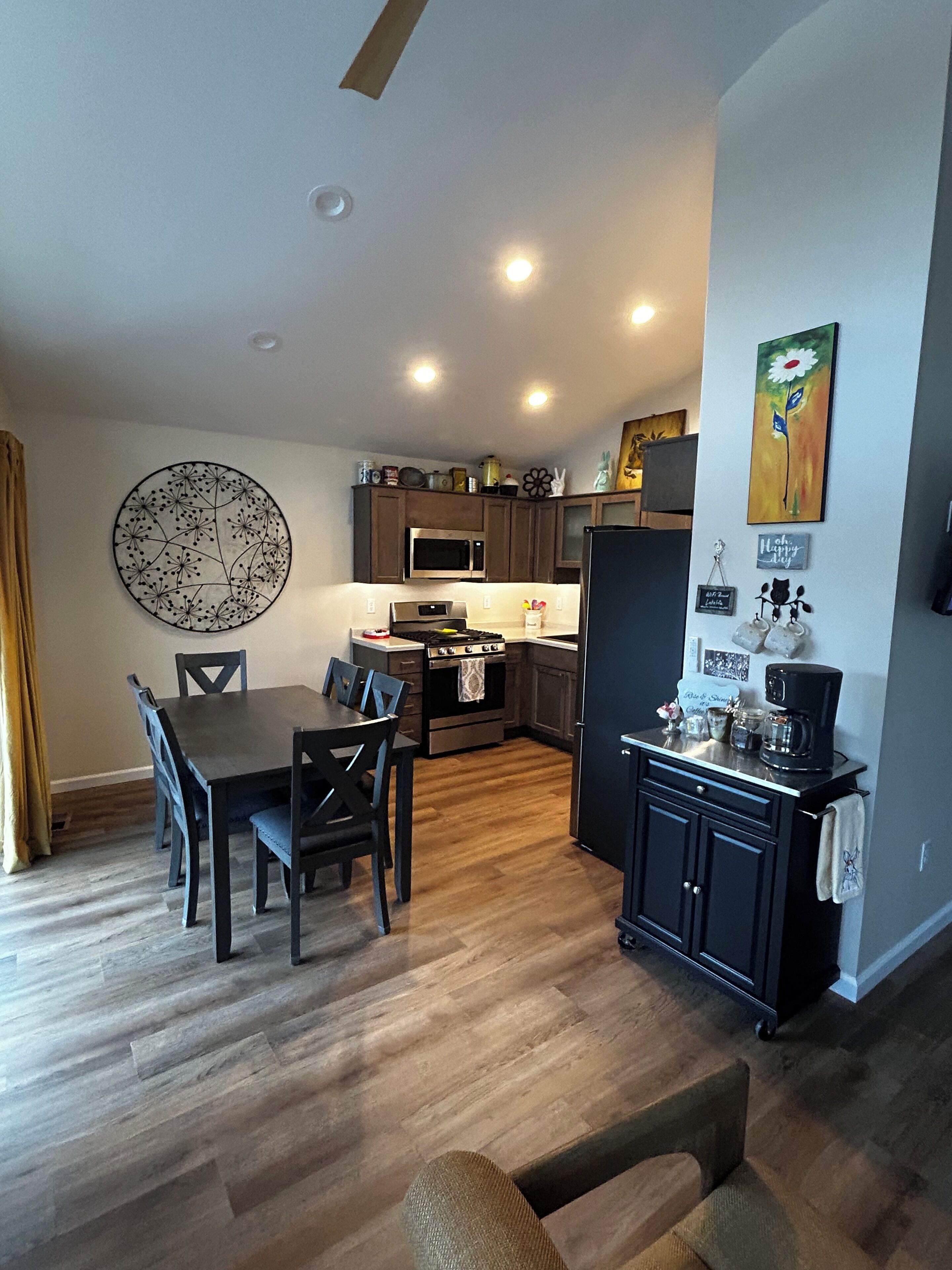 A modern kitchen with wooden cabinets, a dining table with chairs, and a coffee machine.
