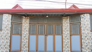 A building with a red roof, stone-patterned walls, and a set of double doors with horizontal slats.