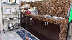 A kitchen with a granite countertop, stainless steel sink, and a dish rack.