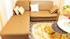 A brown leather sofa with matching cushions, a patterned ottoman, and a small round table with a decorative plate.