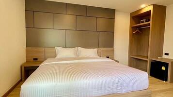 Quarto moderno com cama grande, cabeceira de madeira, mesas de cabeceira e guarda-roupa embutido.