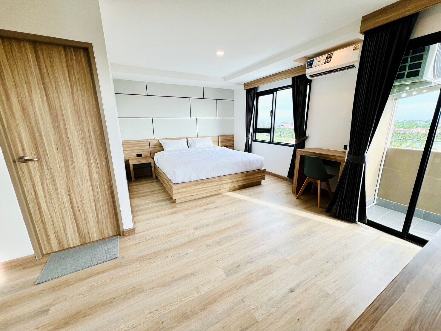 A modern bedroom with a wooden bed, a desk, and a large window.