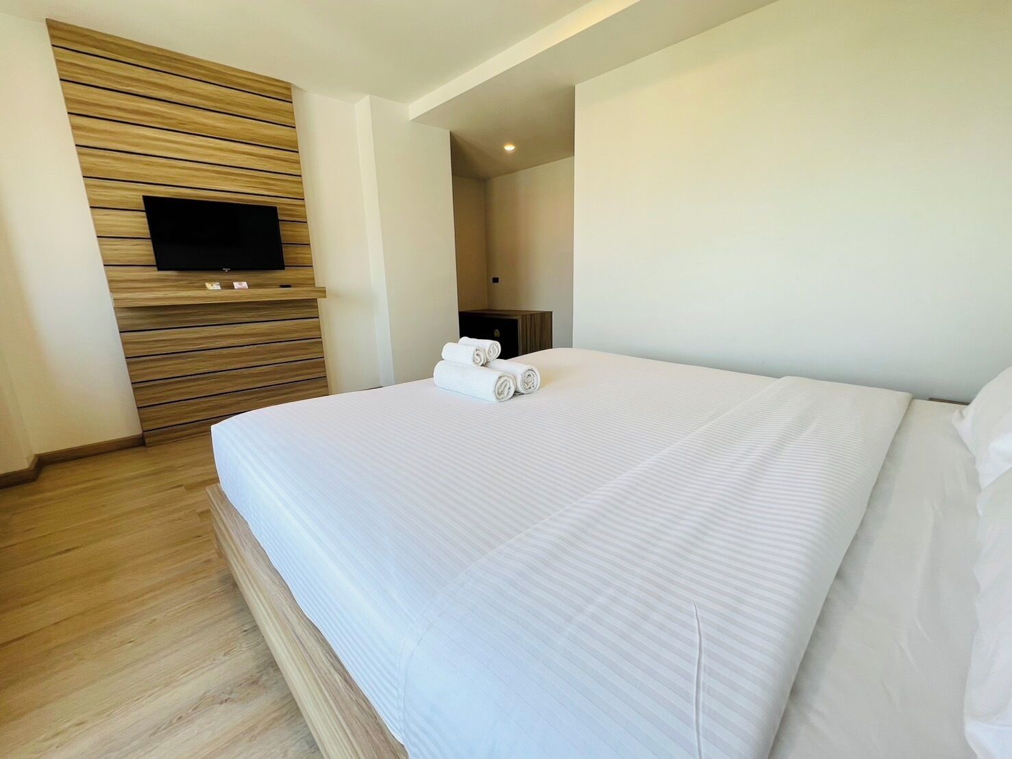 Hotelkamer met een groot bed, houten paneelwand, flatscreen televisie en een klein tafeltje met handdoeken.