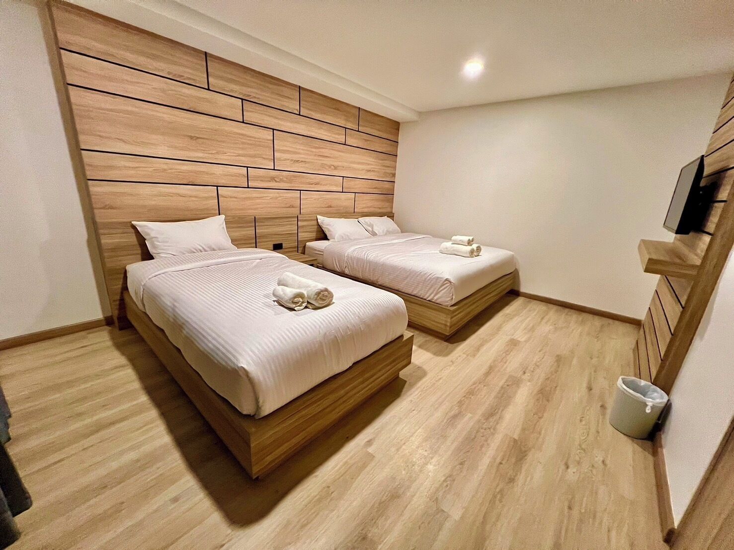 A hotel room with two beds, wooden headboards, and a light-colored floor.