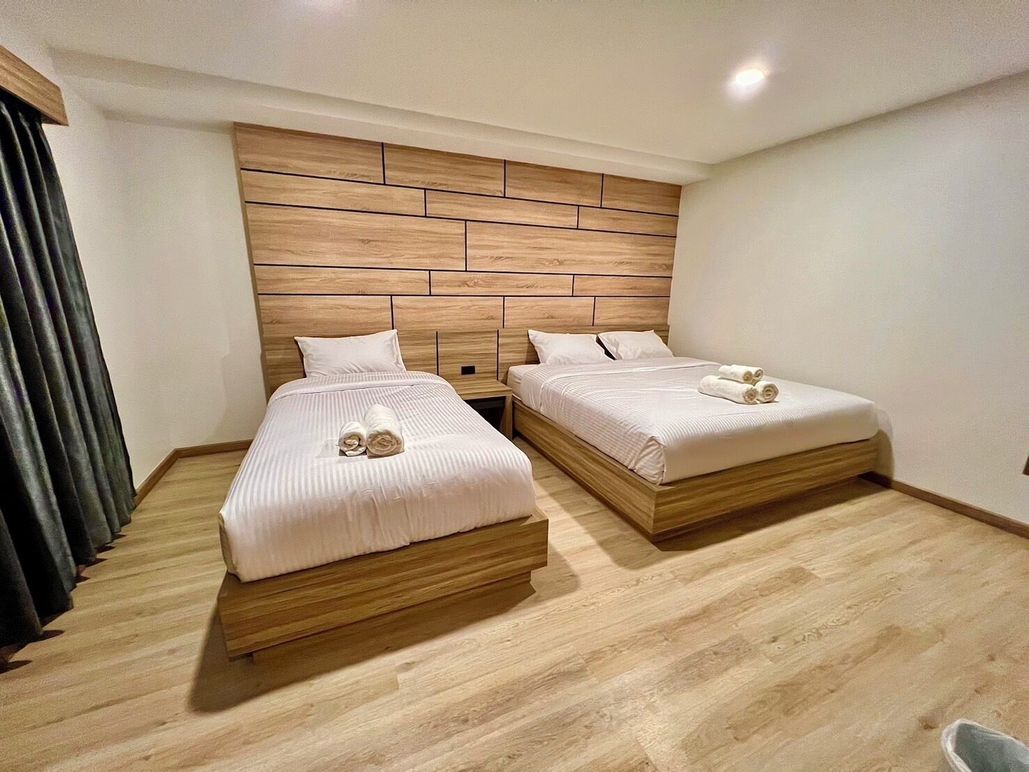 Camera d'albergo con due letti, testiere in legno e arredamento moderno.