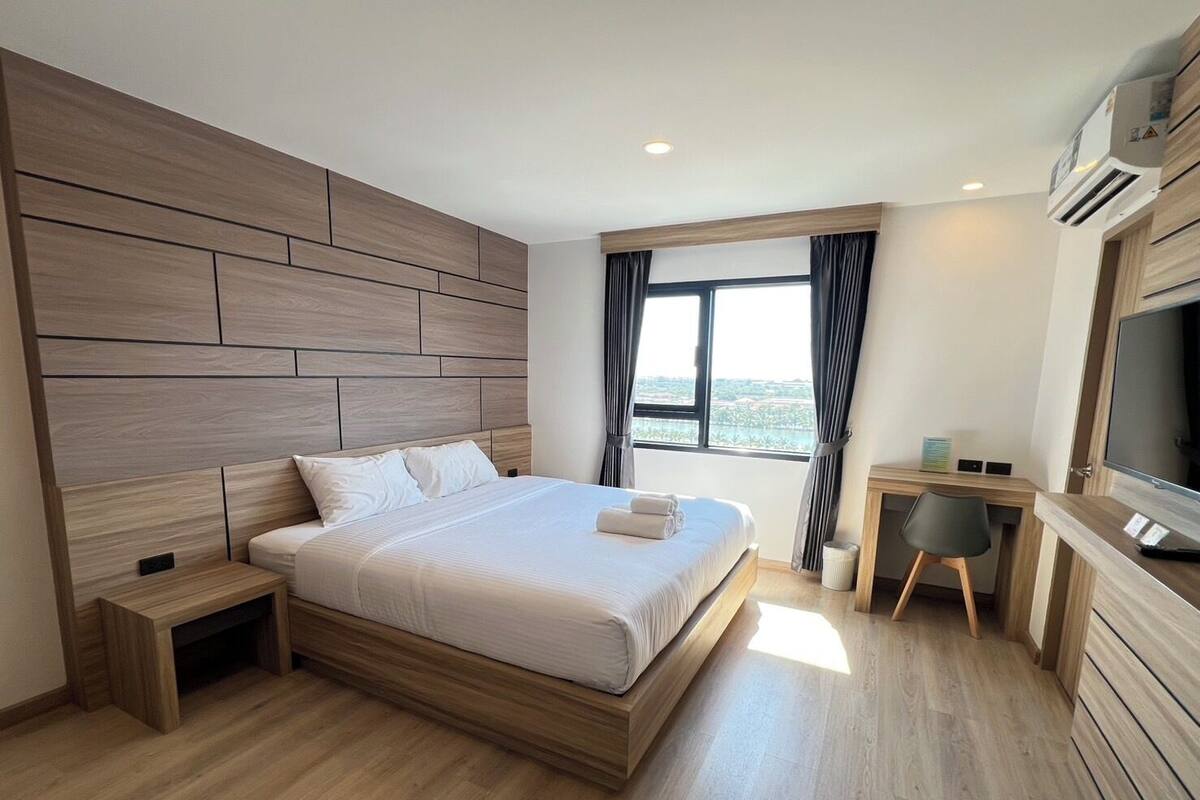 A modern hotel room with a large bed, a desk, and a TV.