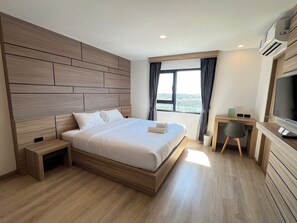 Ein modernes Hotelzimmer mit einem großen Bett, einem Schreibtisch und einem Fernseher.