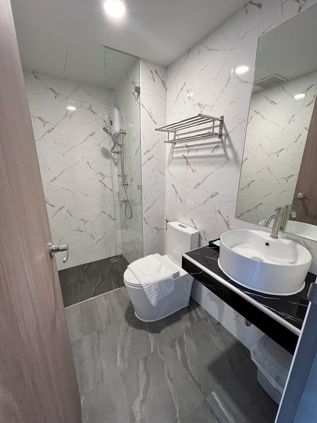 A modern bathroom with a glass-enclosed shower, a toilet, and a vanity with a sink.