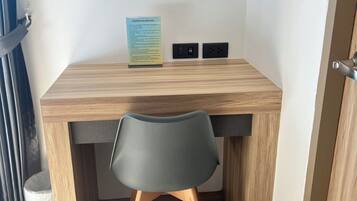 Una habitación pequeña y moderna con un escritorio de madera, una silla negra y un cartel en la pared.