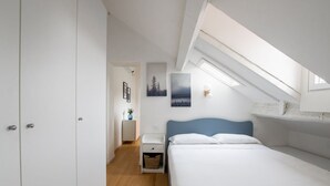 Una camera da letto con un lucernario, un letto, un comodino e una mensola a parete.