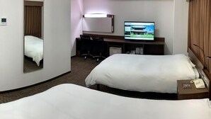 Una habitación de hotel con dos camas, un escritorio, un televisor y un espejo.