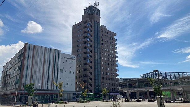 Un hotel moderno con varios pisos, una torre destacada y un edificio de techos planos con señalización.